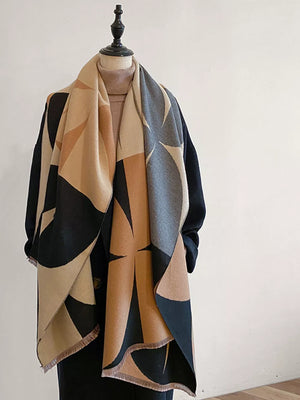 Geometric patterned scarf in tan, black, and grey with fringes, styled on a mannequin.