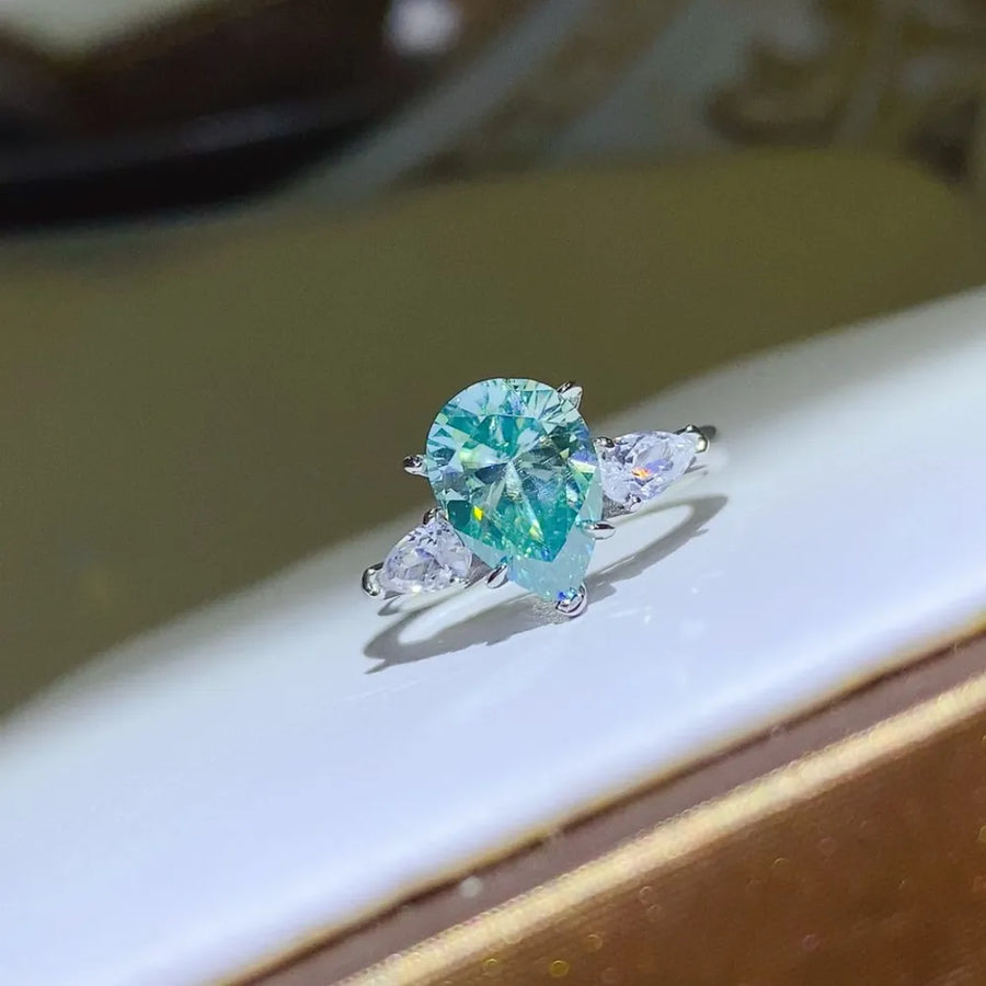 Silver teardrop moissanite and pear-cut trio ring with bright blue center stone.