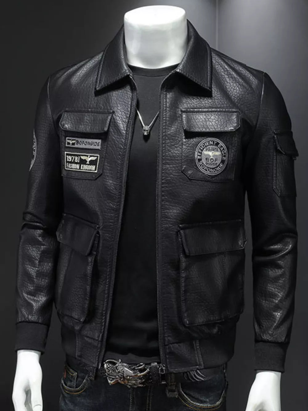 Black leather bomber jacket with multiple pockets and patches, featuring a zip-up front and collared neckline.