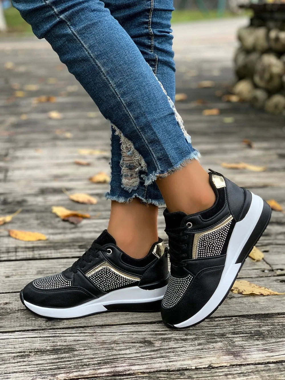 Black platform sneakers with gemstone panels and gold accents.