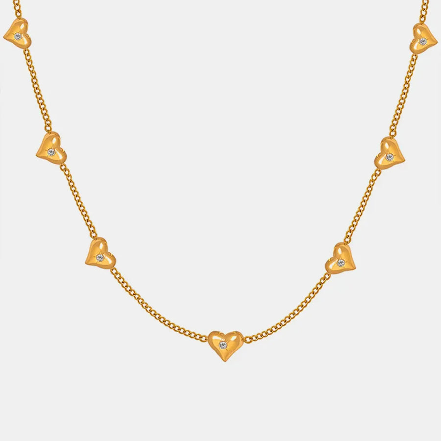 Gold chain necklace with scattered heart charms, each with a small zirconia stone.