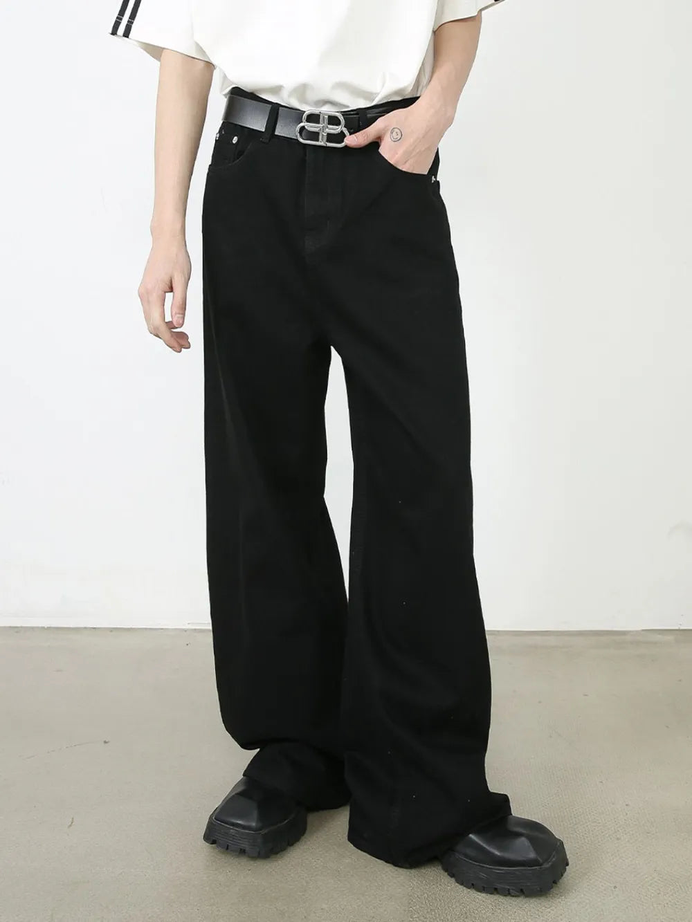 Black denim palazzo trousers with a wide leg and buttoned fly, styled with a belt.