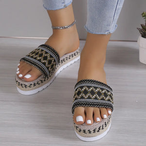 Embroidered platform espadrille slides in black with woven jute sole and white pedicure.