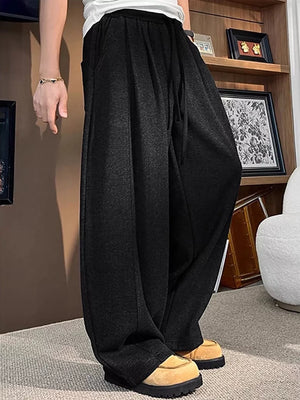 Black sweatpants with a loose fit and drawstring, shown on a man.