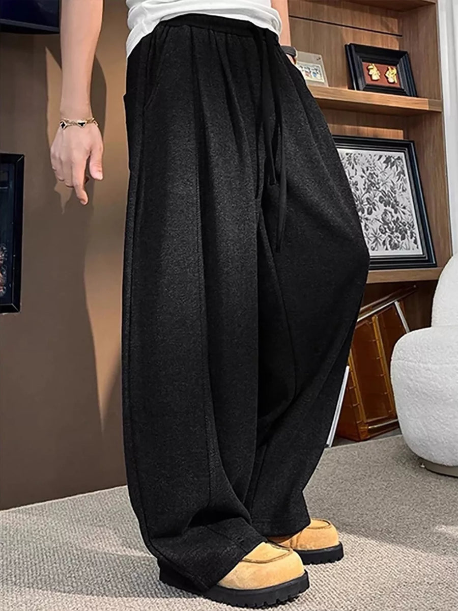 Black sweatpants with a loose fit and drawstring, shown on a man.