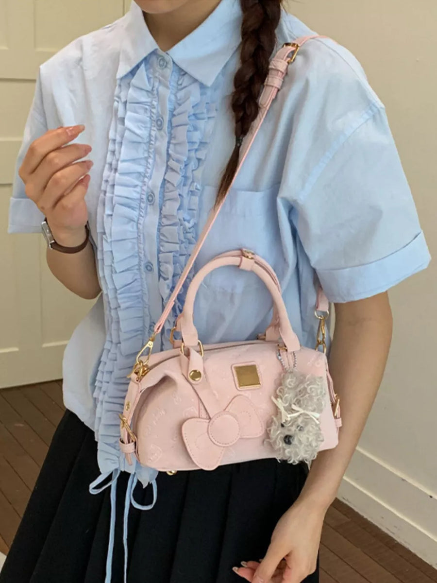 Charming mini crossbody bag in blush pink with bow detail and charm.