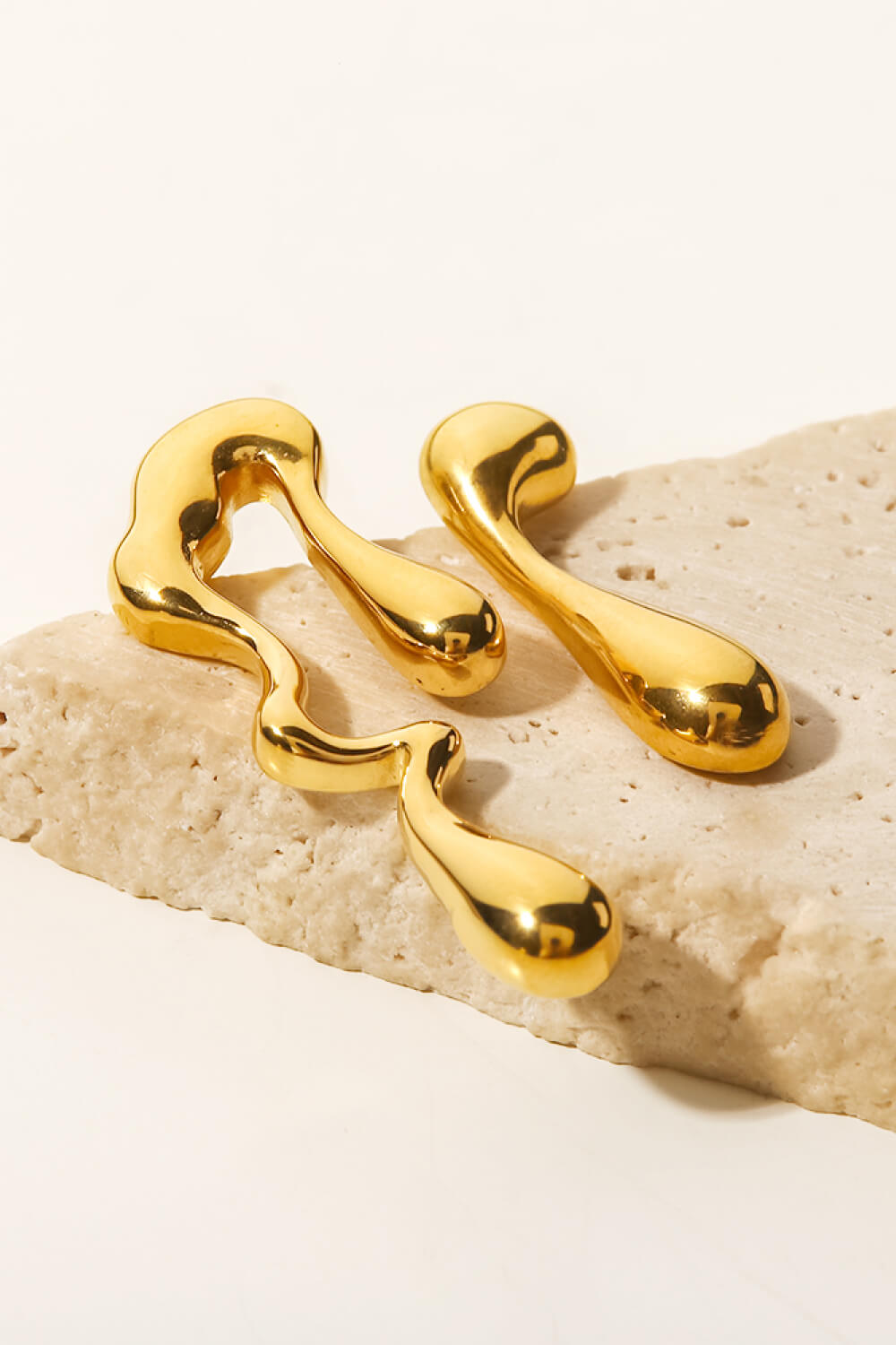 Gold asymmetrical drip earrings with a fluid, artistic design.