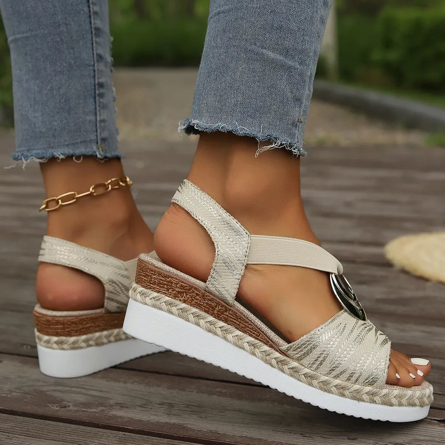 Beige espadrille wedges with metallic accents and a decorative buckle.