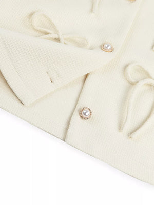 Cream textured knit cardigan with pearl button details and tie accents
