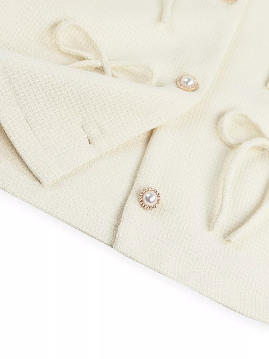 Cream textured knit cardigan with pearl button details and tie accents