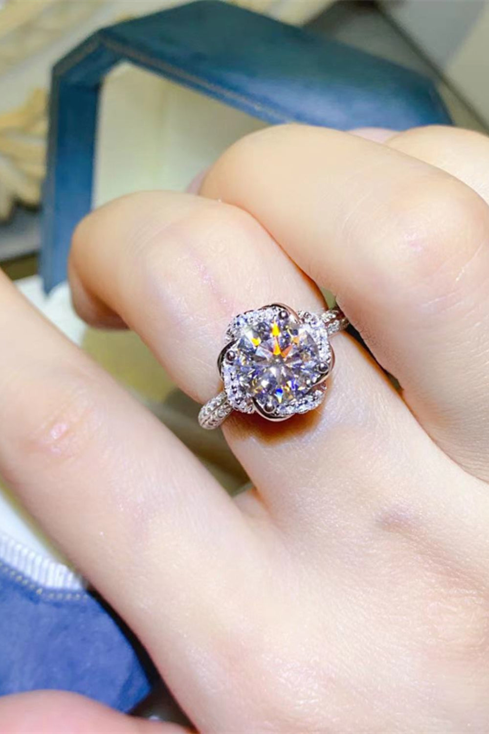 Silver floral halo moissanite engagement ring with a round center stone and pave band.