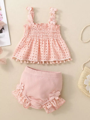Pink eyelet tank with smocked bodice and pom-pom trim paired with ruffled bloomers.