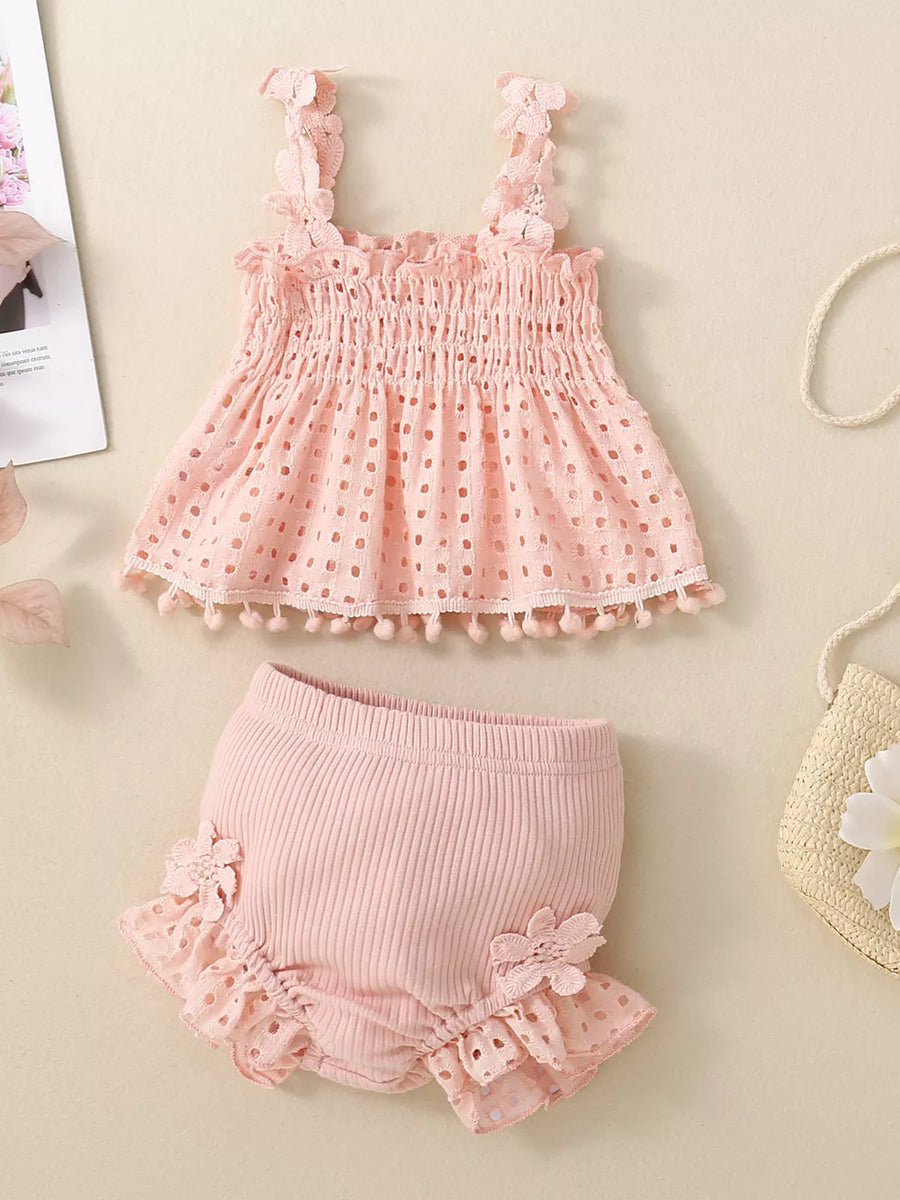 Pink eyelet tank with smocked bodice and pom-pom trim paired with ruffled bloomers.