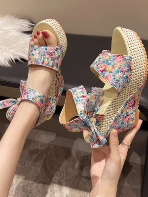 Floral bow wedge sandals with a woven wedge heel and floral print straps.