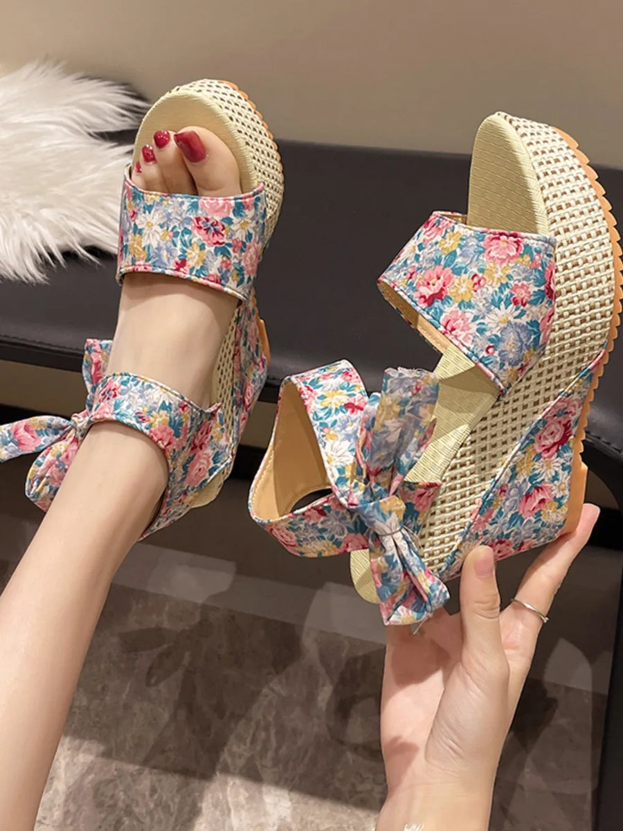 Floral bow wedge sandals with a woven wedge heel and floral print straps.