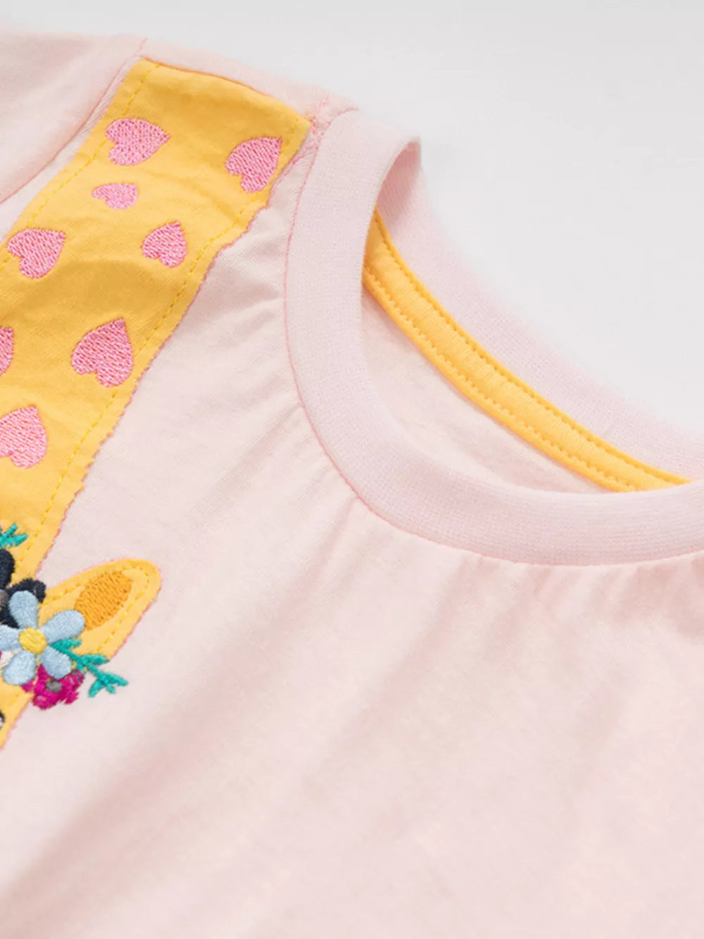 Pink cotton toddler t-shirt with giraffe embroidery and floral charm detail.