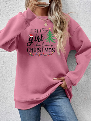Blush pink crewneck sweatshirt with "Just a girl who loves Christmas" graphic and festive lights.