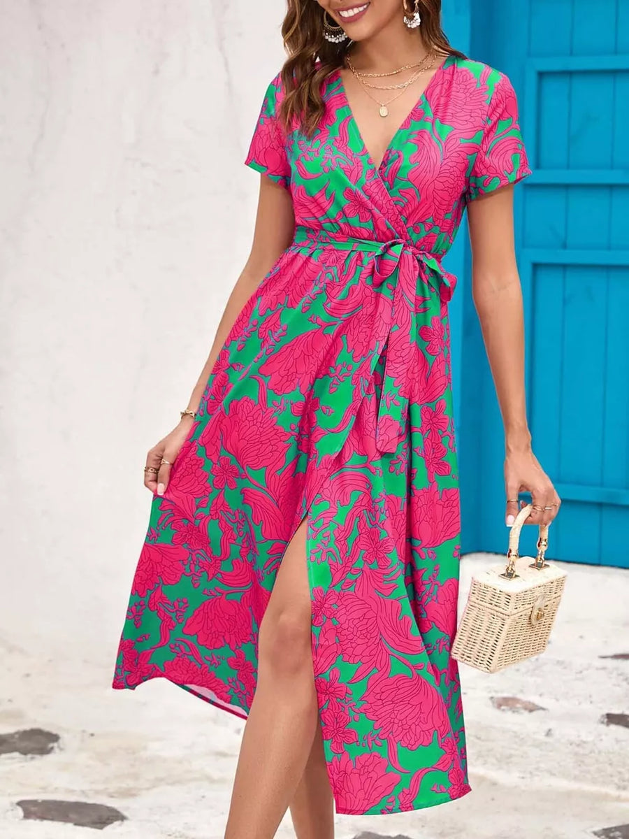 Wrap dress with short sleeves, V-neck, tie waist, and high slit in a pink and green floral print.