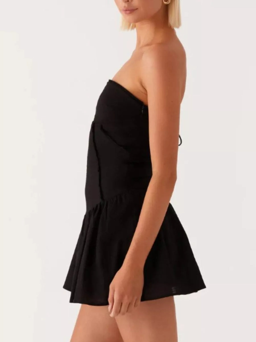 Black ruffled tube dress with back tie detail and flared skirt.