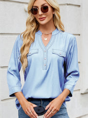 Light blue denim henley blouse with utility pockets and button-up neckline.