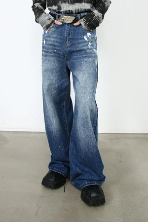 Painterly denim palazzo trousers in medium wash with artistic paint splatters and a wide leg.