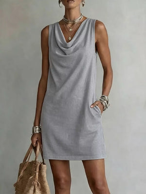 Sleeveless grey cowl neck mini dress with pockets and layered necklaces.