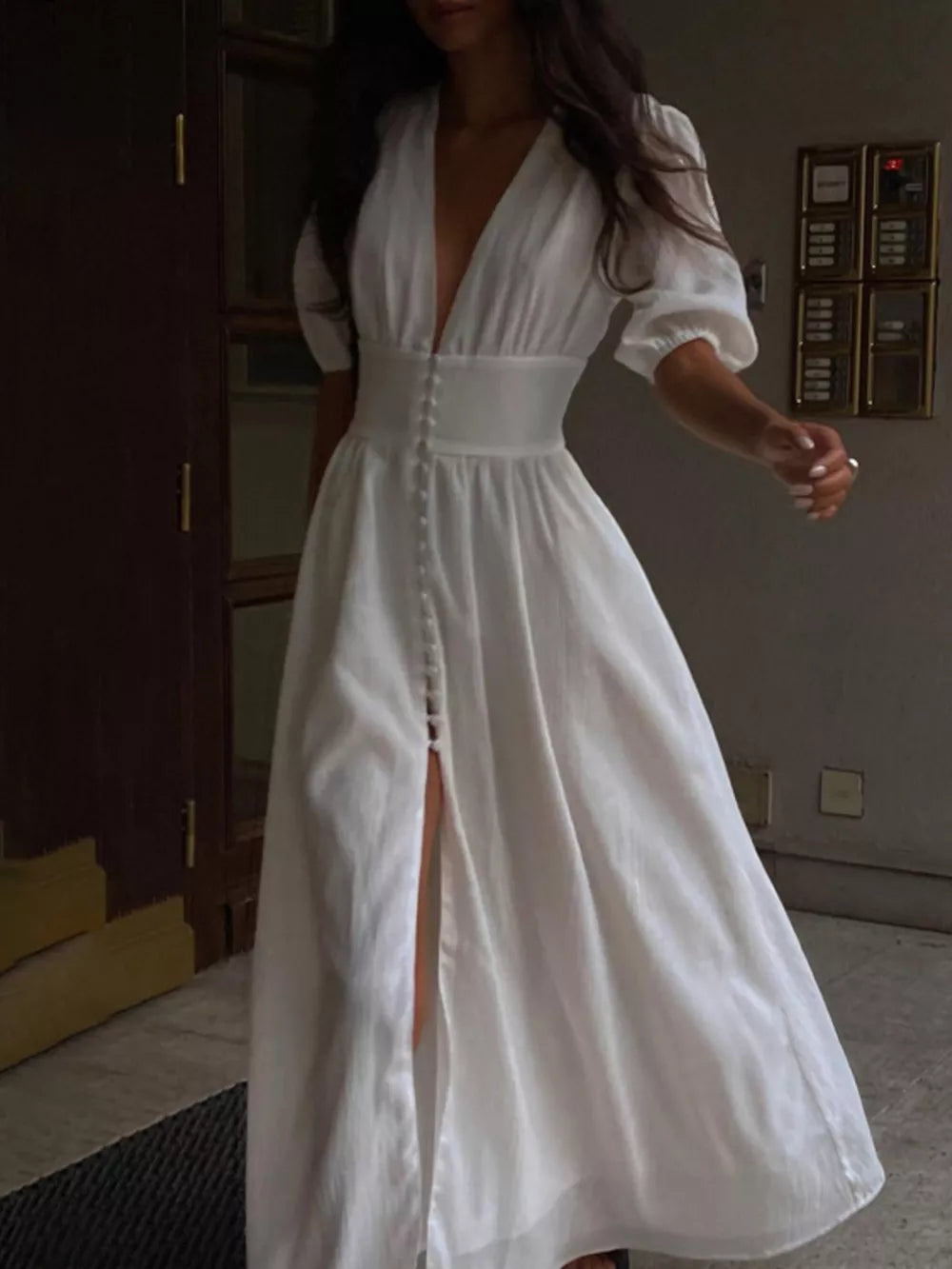White linen maxi dress with deep V-neck, puff sleeves, button front, and high slit