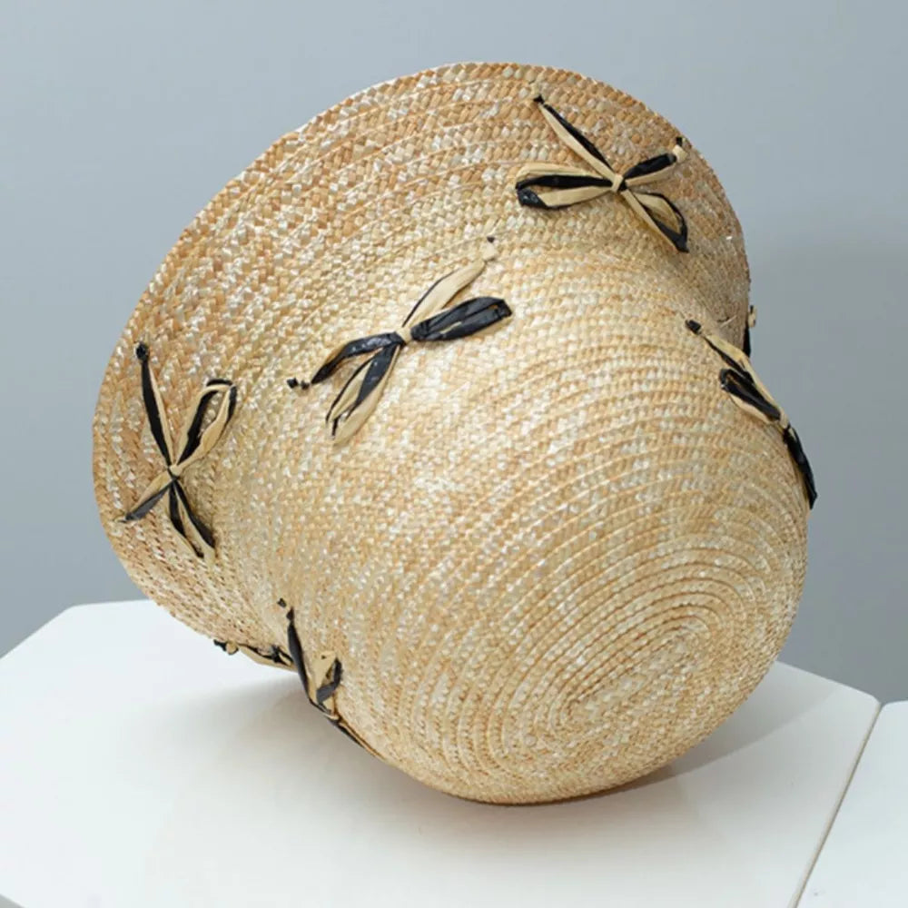 Straw bucket hat in natural with black and tan bowknot details.