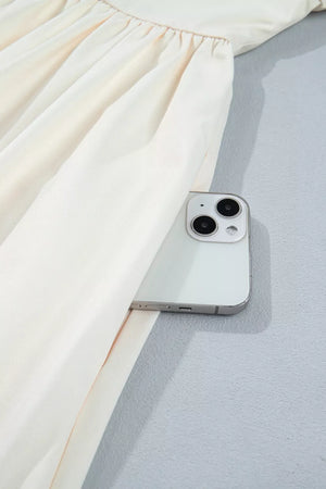 Cream floral puff sleeve A-line dress with side pocket detail shown with a phone.