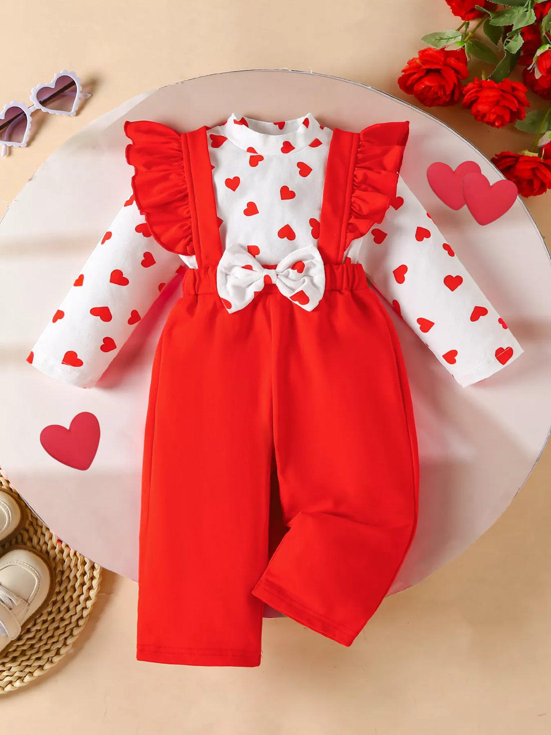 Baby girl red suspender pants and white heart print top set with ruffle sleeves and bow detail.