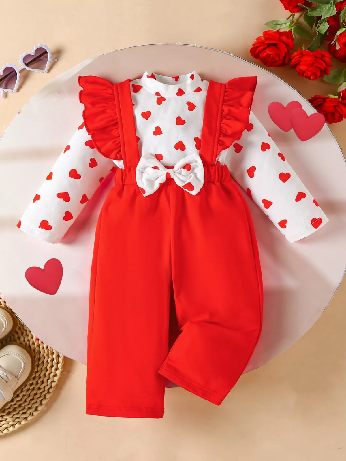 Baby girl red suspender pants and white heart print top set with ruffle sleeves and bow detail.