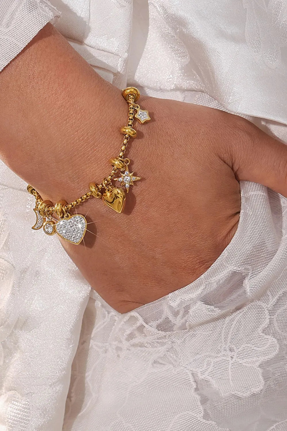 Gold charm bracelet with moon, heart, and star charms, some with zirconia details.