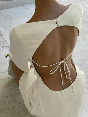 Cream backless dress with tie detail and button accents