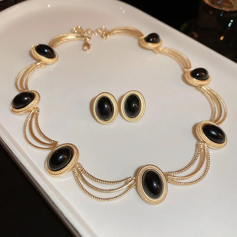 Gold oval gemstone necklace and matching earrings set with black stones