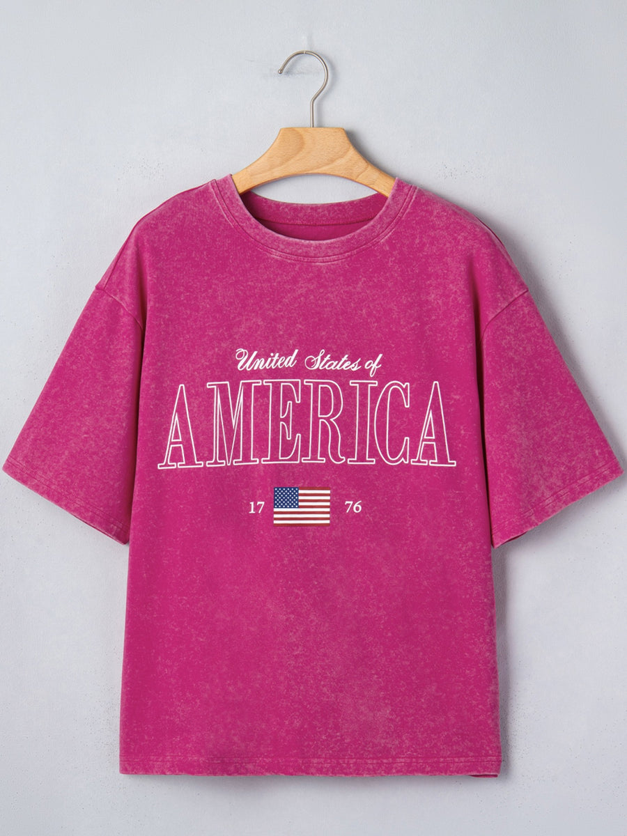 Patriotic graphic cotton t-shirt in magenta with "United States of America" text and US flag graphic.