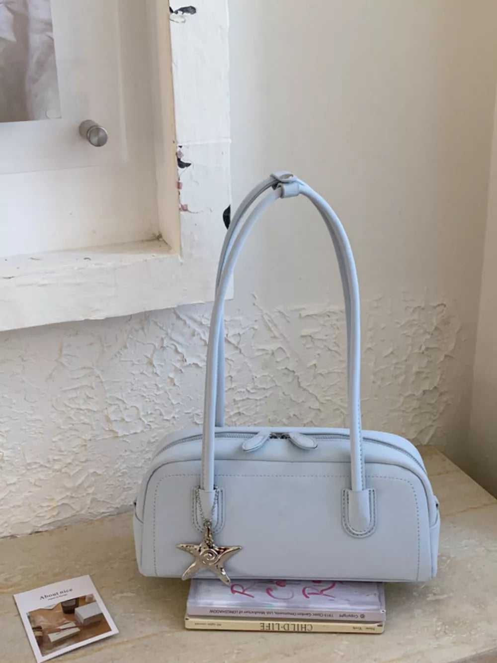 Light blue leather shoulder bag with star charm and double zipper closure