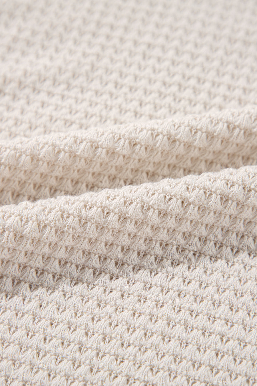 Beige waffle knit V-neck top with slit hem detail.