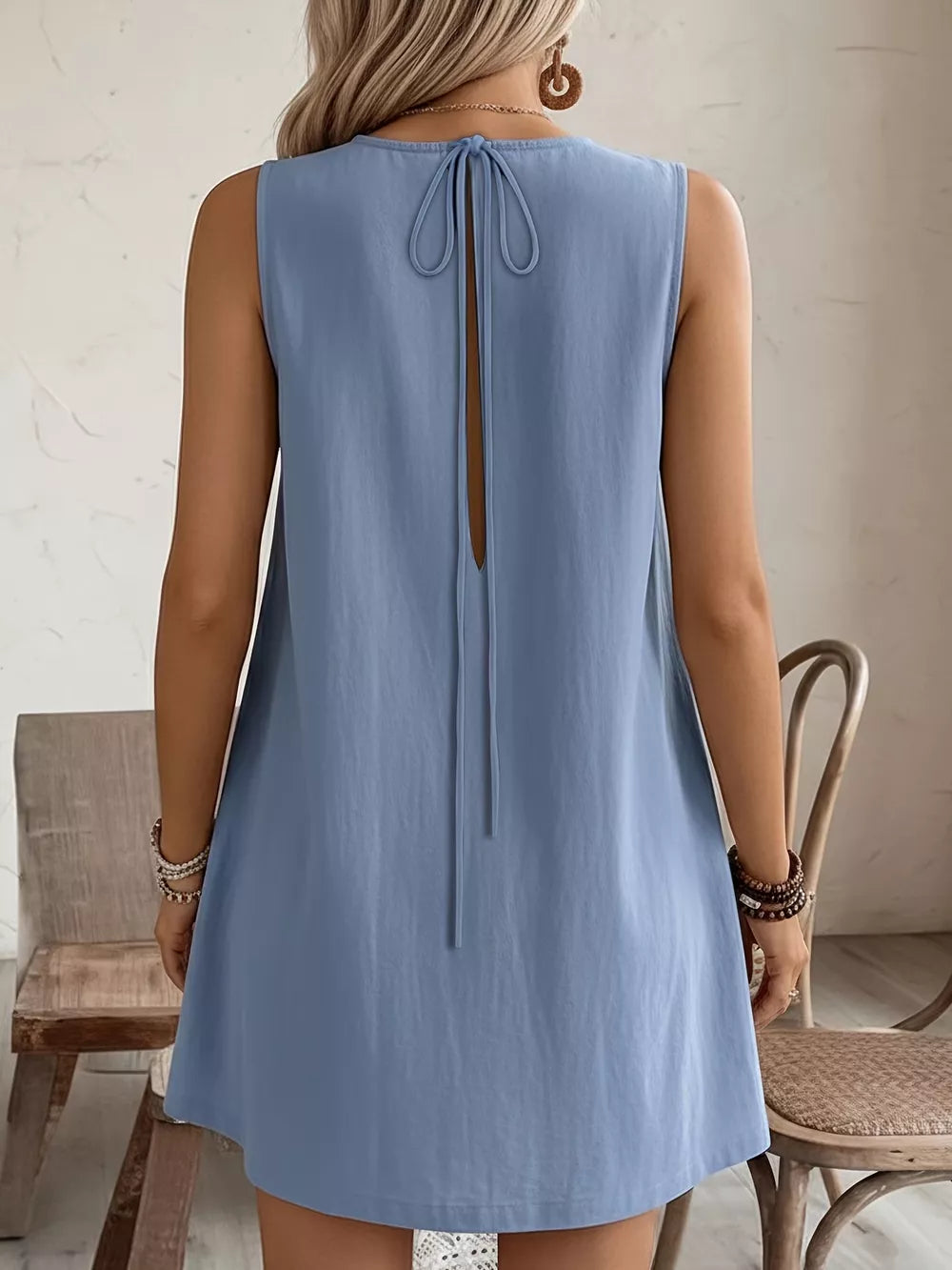 Light blue sleeveless dress with tie-back detail and open back.
