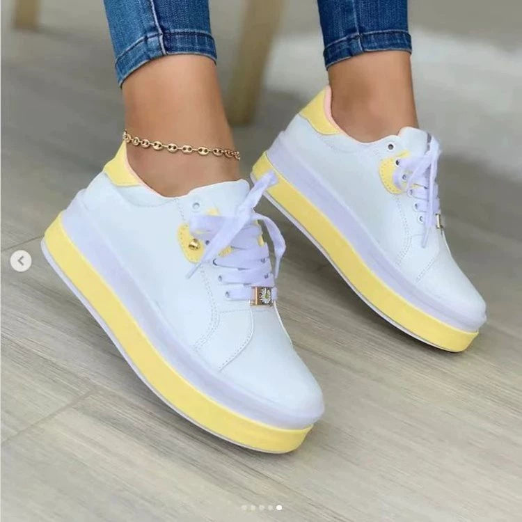 White lace-up platform sneakers with yellow accents and gold hardware.