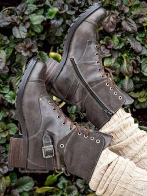 Brown leather combat boots with contrast cuff, laces, buckle, and side zipper.