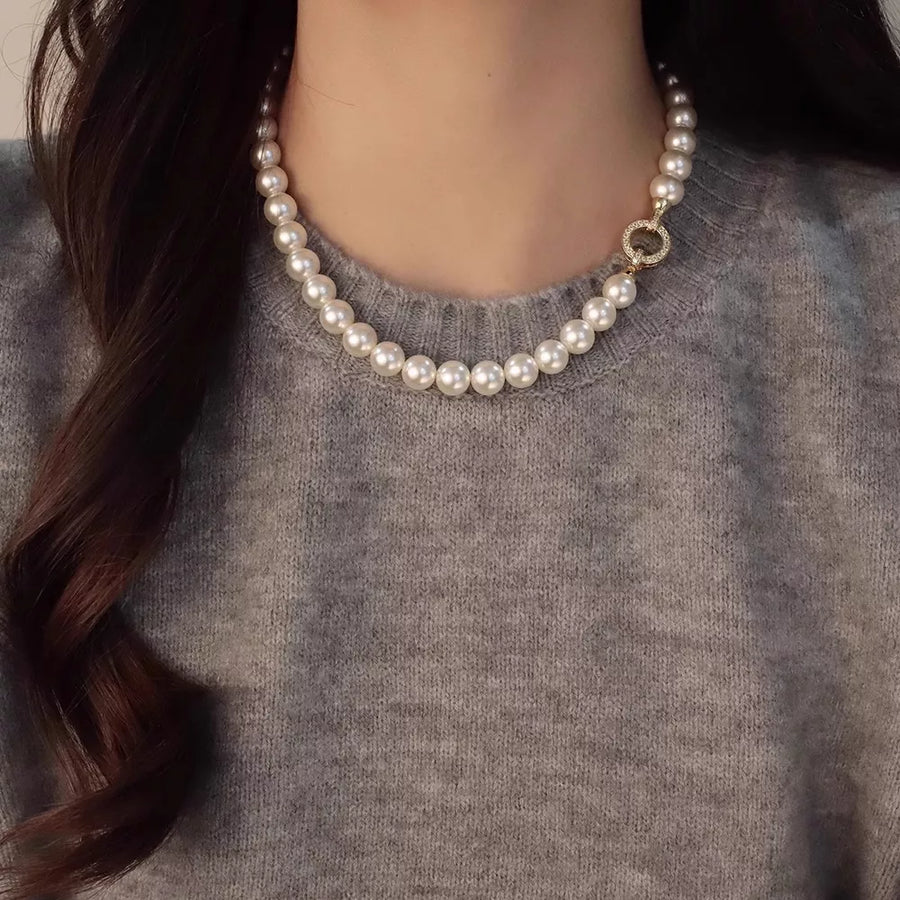 Lustrous pearl choker necklace with ornate gold clasp detail.