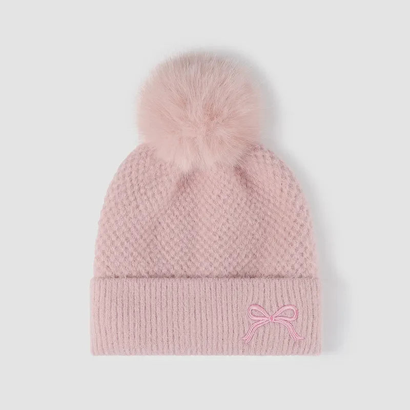 Pink textured knit baby beanie with pom-pom and embroidered bow detail