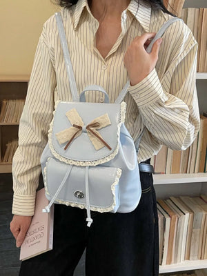 Blue mini backpack with lace trim, bow detail, and drawstring closure.
