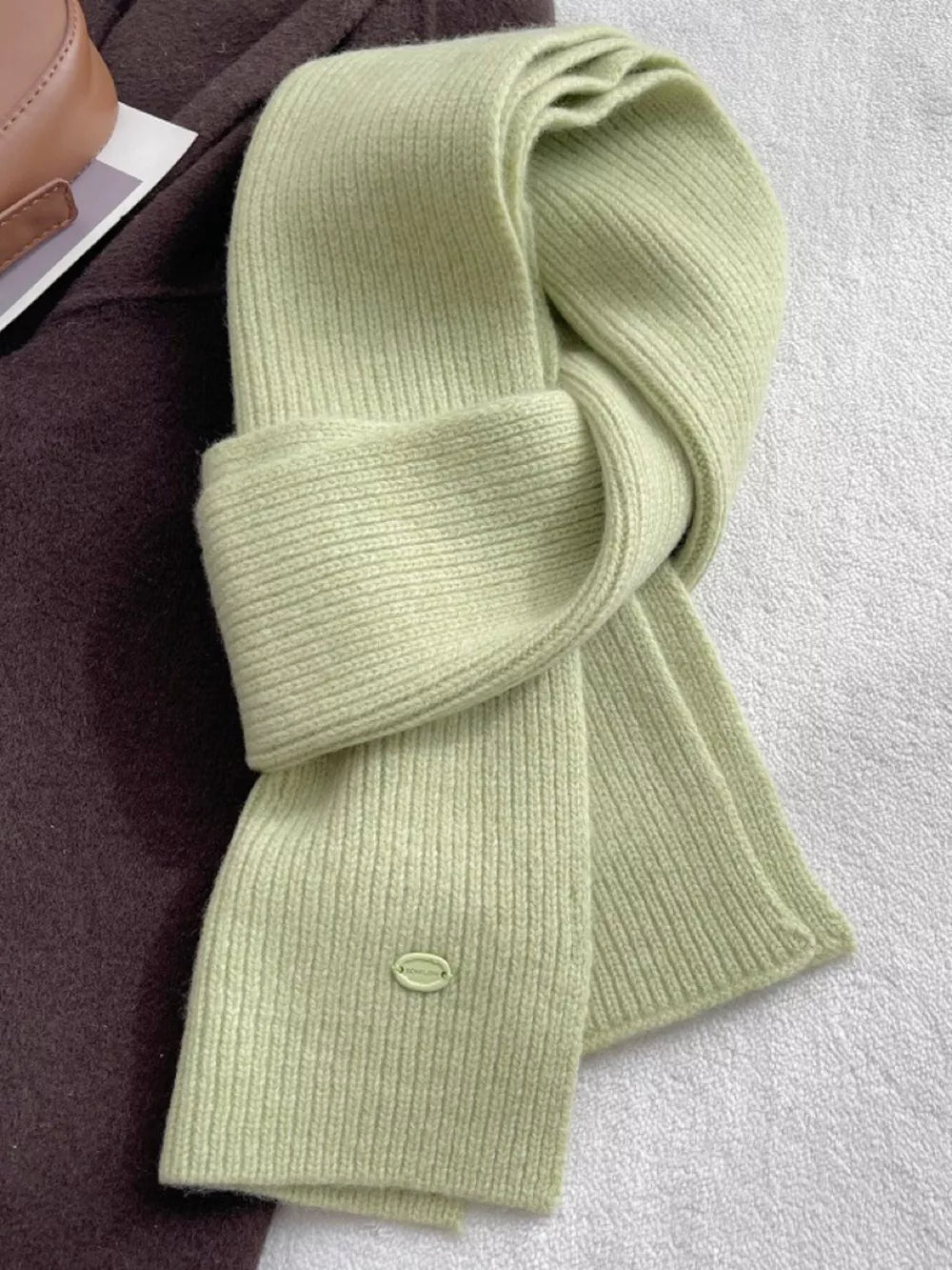 Luxe ribbed knit wool scarf in Gum Leaf green with a small oval logo detail.
