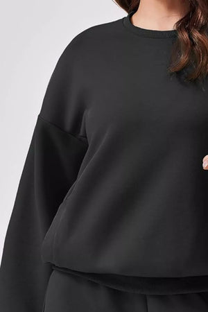 Black crewneck sweatshirt with ribbed collar and cuffs, part of a loungewear set.