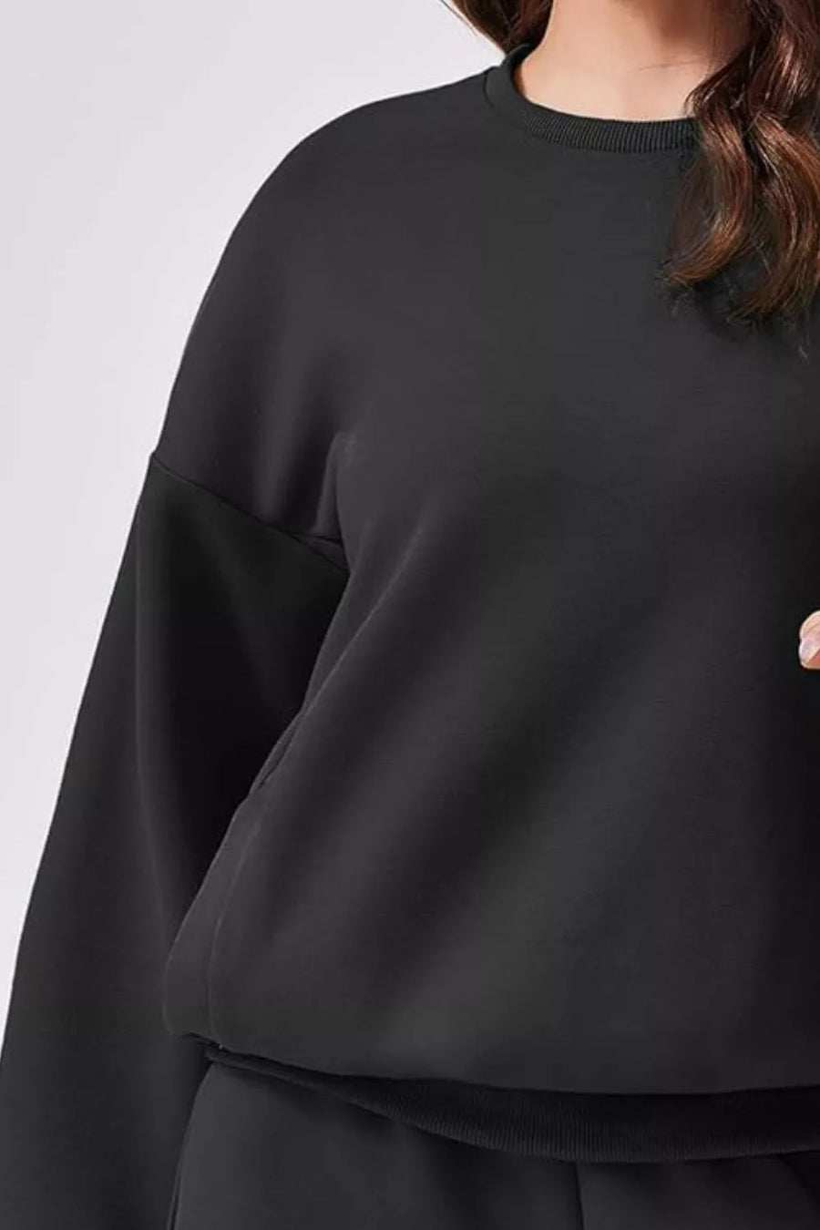 Black crewneck sweatshirt with ribbed collar and cuffs, part of a loungewear set.