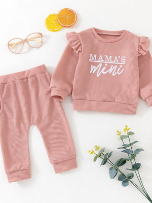 Pink cotton waffle knit toddler set with ruffled sleeves and "Mama's Mini" graphic.