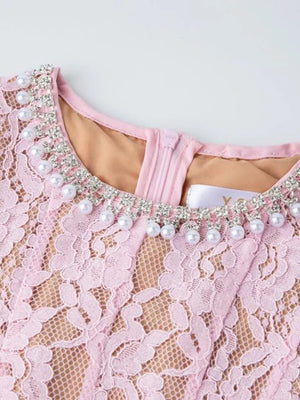 Pink lace midi dress with pearl and rhinestone neckline detail.