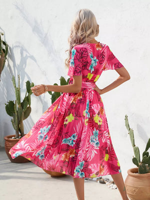 Hot pink tropical pleated midi dress with belt and short sleeves.
