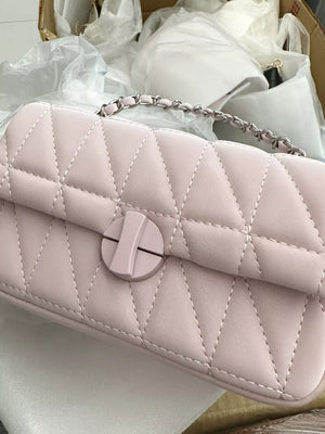 Pink quilted flap chain bag with a circular closure and silver chain strap.